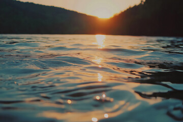Warm sunlight reflecting on gently rippling lake water surface at sunset, creating a tranquil and scenic view