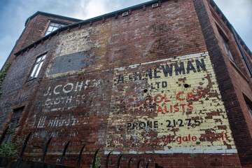 Ghost signs from old businesses fading on brick wall