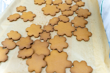 Snowflake-shaped cookies are ready to be decorated with frosting on baking paper. The process of cooking a New Year's or Christmas treat, recipe.