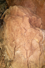 A large rock with a rough surface. The rock is brown and has a lot of texture. It looks like it has been weathered by the elements over time.