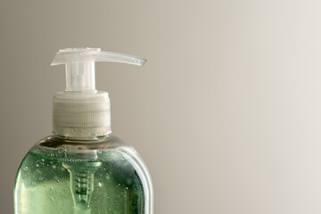 Close up of upper part of soap dispenser, filled with green soap. White space.