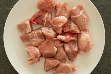 Chopped raw pork meat on a white plate on black background.