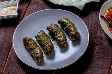 dolma with rice and meat and sauce and hummus in a plate on a wooden table