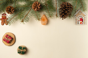 Beige background with Christmas tree branches, pine cone, toys and gift boxes. Flat lay, top view. Copy space