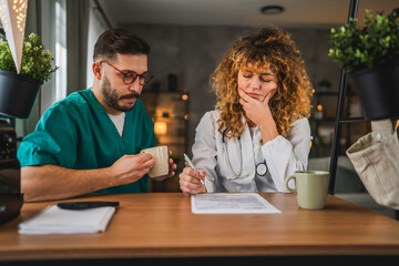 two doctors colleagues man and woman review patient files together