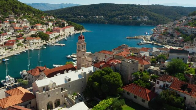 The ancient building of the parish church of Saint Jerome of Stridon in the port town of Pucisca (Puči&scaron;ća) on the island of Brac (Brač), Croatia. A bell tower with a clock on a stone church tower.