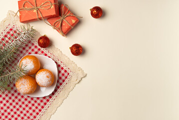 Christmas tree branch with oranges dusted with snow, gift boxes and balls on beige background. Flat lay, top view. Copy space