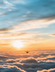 Naklejka premium Airplane flying above clouds during a colorful sunset.