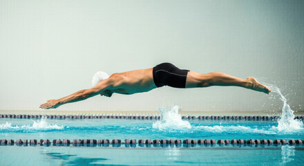 Male athlete diving into pool during swim race