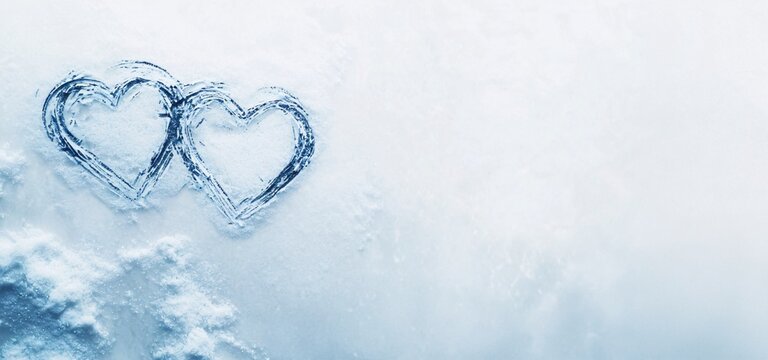 Two blue heart love design on the left drawn on white bluish snow background with copy space