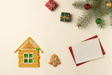 Blank card with sweets house and Christmas tree branch on beige background. Flat lay, top view. Space for text.