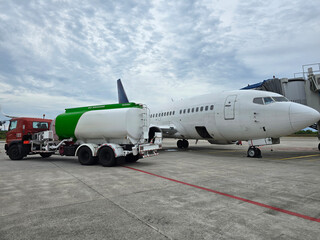 A tanker truck loaded with fuel is refueling a plane at the airport.