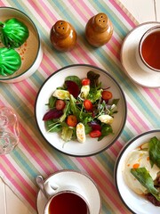 Top view of a vegetable salad that is surrounded by other dishes and drinks