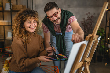 Adult caucasian couple paint on canvas easel at home together