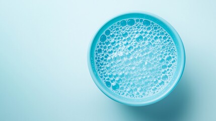 A close-up of a frothy blue beverage in a round glass against a light background.