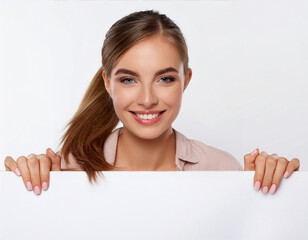 Fototapeta premium Young Woman Smiling and Peeking Behind a Blank Placard, Cheerful Isolated Concept on White Background