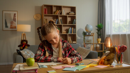 Glad little Caucasian schoolgirl daughter studying girl learn at home kid writing task notebook parent woman walk mom smile check homework mother female touch child care pupil family education custody