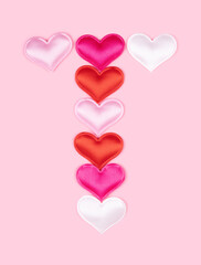 Letter T made of glossy atlas hearts isolated on solid pink background. Love alphabet concept. One letter of the set of heart's font easy to stacking.