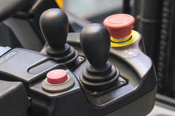 A forklift control panel with a red button and two black buttons. © Aleksandr Matveev