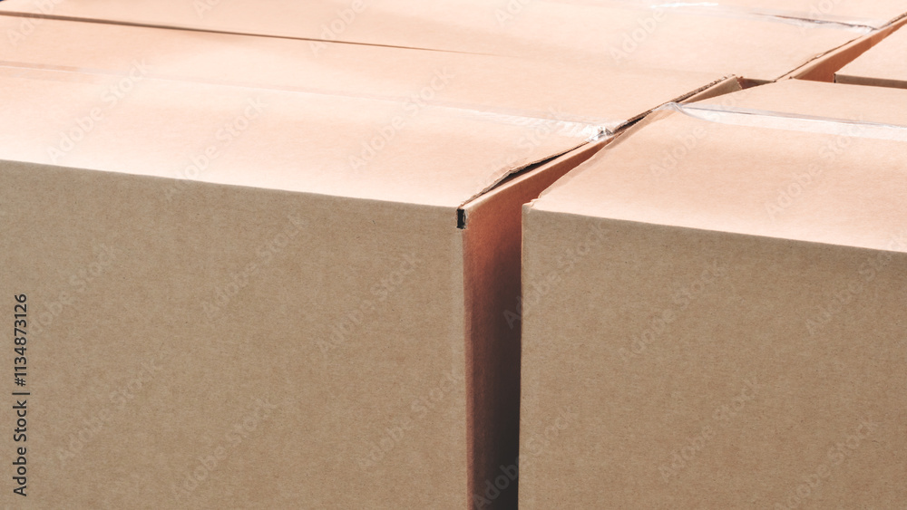 Poster A stack of cardboard boxes with a white tape on the top. The boxes are brown in color