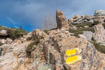 Wanderzeichen am Bavella Gebirge mit Berggipfel im Nebel, Korsika