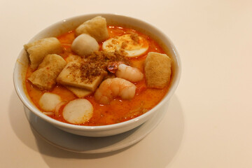 close up of Singaporean Malaysian soup laksa noodles with fishballs, tofu bean curd, prawns, shrimps and fish slice
