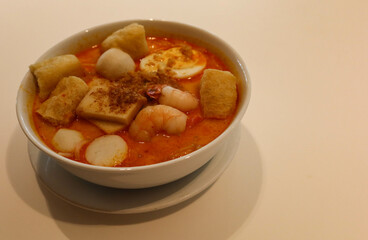 close up of Singaporean Malaysian soup laksa noodles with fishballs, tofu bean curd, prawns, shrimps and fish slice