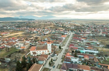 Views from above showcase the quaint village of Rasnov, nestled in the Piatra Craiului region of Brasov, highlighting its distinctive homes and expansive farmland