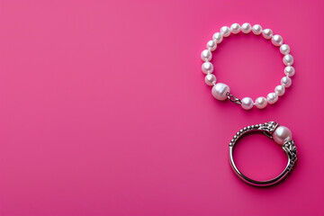 Top view of a silver anklet and pearl ring on a fluorescent pink background.