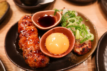 close up of Japanese minced chicken meat skewer with raw egg and soy sauce for dipping