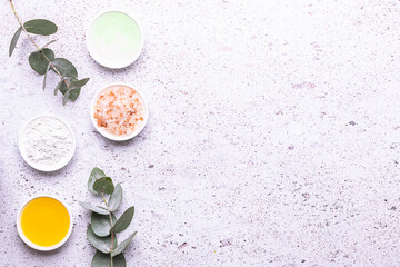 Set of organic eco skin care products in white unbranded containers , beautiful flowers and eucalyptus leaves on marble background top view.
