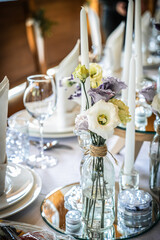 Wedding table decoration with flowers and candles. The elegant wedding table for guests. Stylish table set for wedding dinner