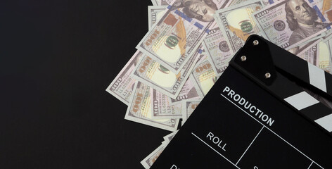 Clapper board and us dollar banknotes on balck background