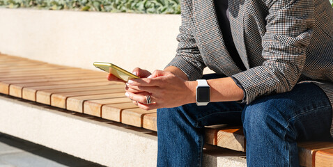 Digital devices in urban lifestyle. Modern businesswoman texting on a smartphone outdoors on a city street.
