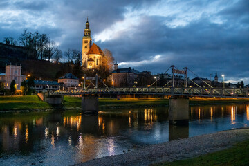 Obraz premium Night view of Our Lady of the Assumption church, Kirche Maria Himmelfahrt, on the foothills of the Monchsberg in Salzburg, Austria, along Salzach River