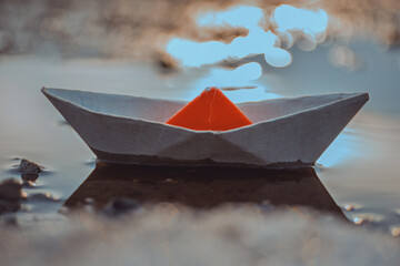 Paper Boat with Orange Sail Reflecting in Water, Symbolizing Minimalist Creativity and Childhood Nostalgia