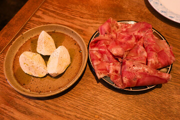 close up of mozzarella cheese in three quarter on a plate and a dish of parma ham cold cut for appetizer
