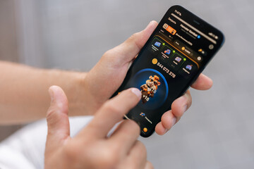 Closeup cropped shot of unrecognizable senior gamer male playing mobile crypto game to earn cryptocurrency, tapping on screen for potential profit in fast-paced digital world of online gaming finance.