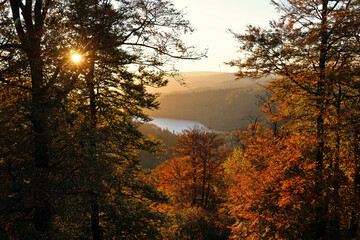 Der Stausee Nonnweiler während des Sonnenuntergangs in malerischer Natur im Herbst im Nationalpark Hunsrück-Hochwald. Aussicht von den Premium-Wanderwegen Dollbergschleife und Saar-Hunsrück-Steig.