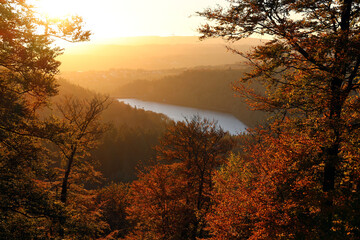 Fototapeta premium Der Stausee Nonnweiler während des Sonnenuntergangs in malerischer Natur im Herbst im Nationalpark Hunsrück-Hochwald. Aussicht von den Premium-Wanderwegen Dollbergschleife und Saar-Hunsrück-Steig.