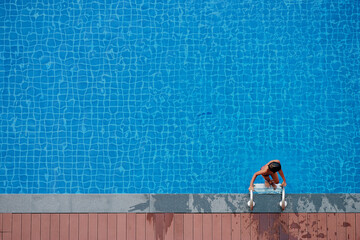 Overhead View of Woman Climbing Ladder in Blue Swimming Pool