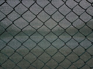 Fototapeta premium Close-up of wire mesh fence. Green sun protection and green wire fence. Safety nets. Green steel wire chain link net fence. Galvanized pvc coated chain link. Garden steel fence background. 