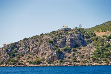 Naklejka premium Scenic view of a quaint coastal village featuring Mediterranean-style architecture nestled by the sea. The vibrant blue sky enhances the tranquil beauty of the serene landscape.