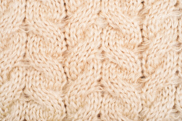 Cozy background of beige knitted texture with cables and braids