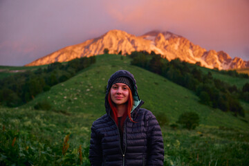 portrait of a young girl against the background of mountains during sunset on a hike