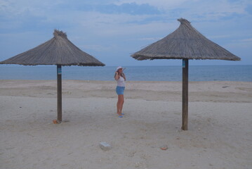 beach chairs and umbrellas on beach a woman is walking on the sea and beach, you can see the sedentary wind