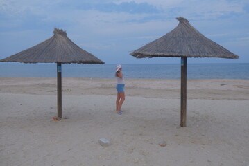 beach chairs and umbrellas on beach a woman is walking on the sea and beach, you can see the sedentary wind