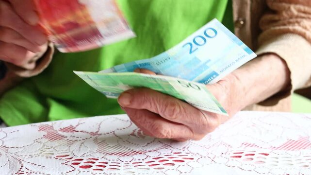 Elderly woman shuffles several banknotes in her hand. Norwegian kroner money, Financial concept. Inflation and financial problems of pensioners in Norway