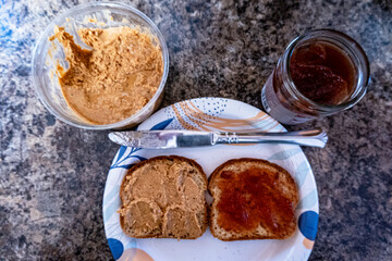 top down open face peanut butter and jelly sandwich on paper plate
