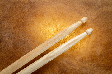 classic 5A wooden drumsticks against backlit drum goat skin